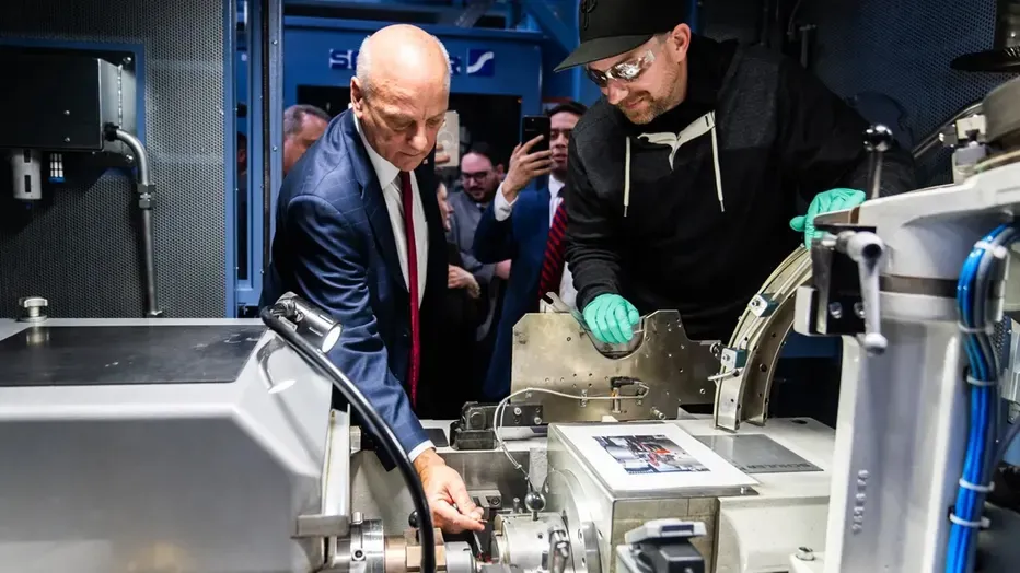U.S. Treasurer Brandon Beach and a Mint employee place the final penny into a coining press during the ceremonial last strike at the U.S. Mint in Philadelphia on November 12, 2025
